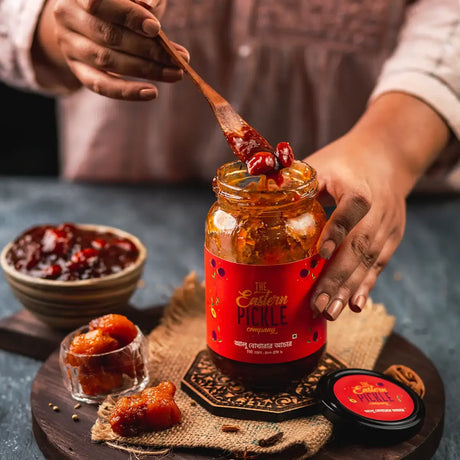 Someone is picking up Alu Bukhara Pickle with a spoon from a big jar | Eastern Pickle